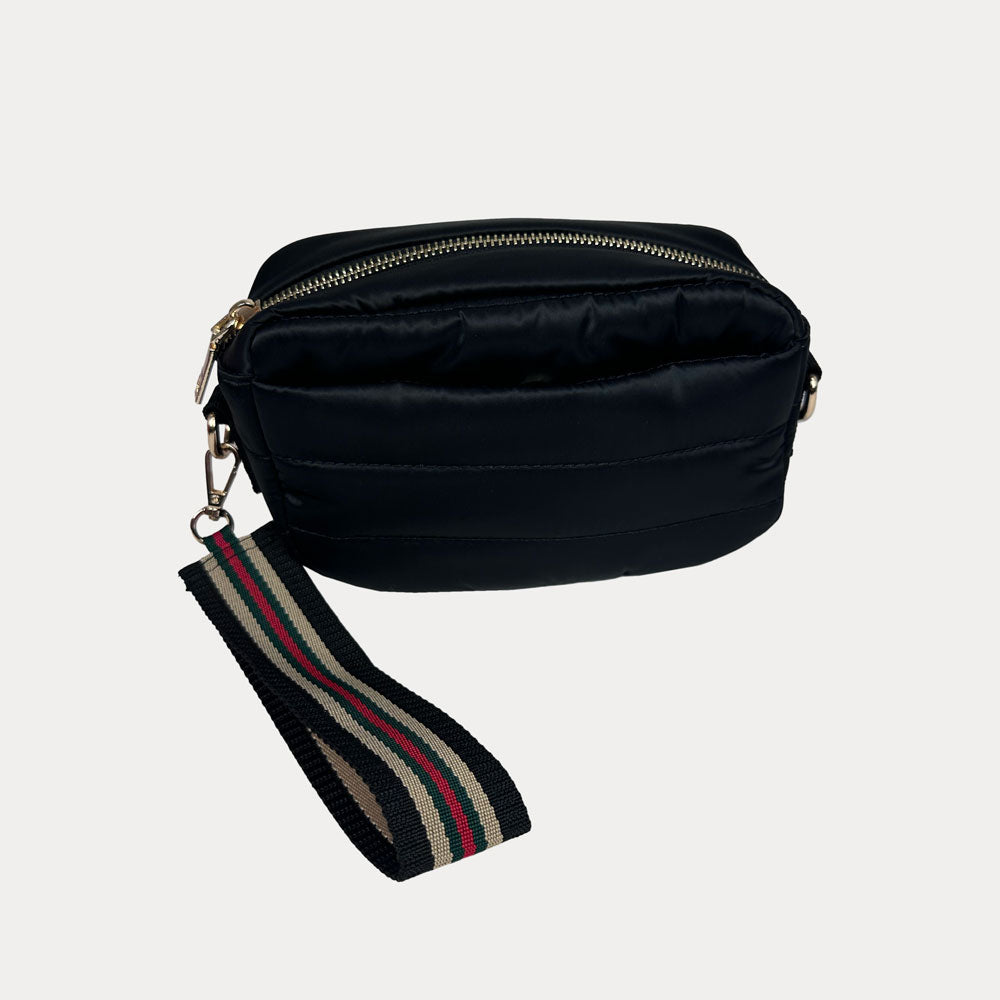 Black crossbody bag with a striped wristlet strap on a light gray background