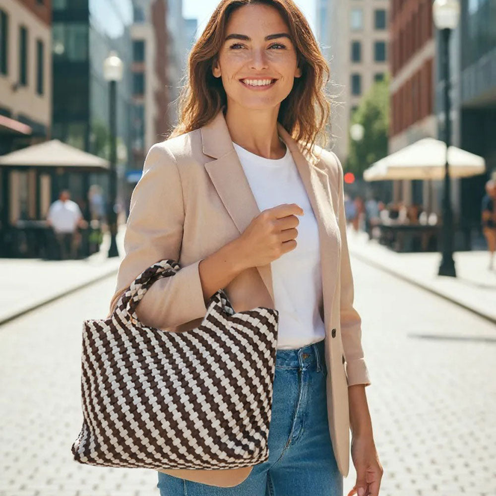 Woman on a sunny city street, posing with a chocolate/ecru striped tote on her arm.