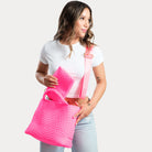 woman wearing the lily hot pink woven neoprene tote as a crossbody