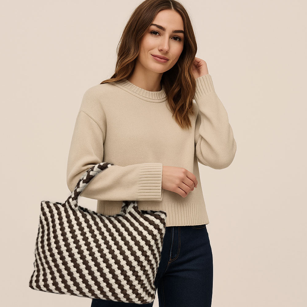 Woman holding a black and white patterned bag against a beige background