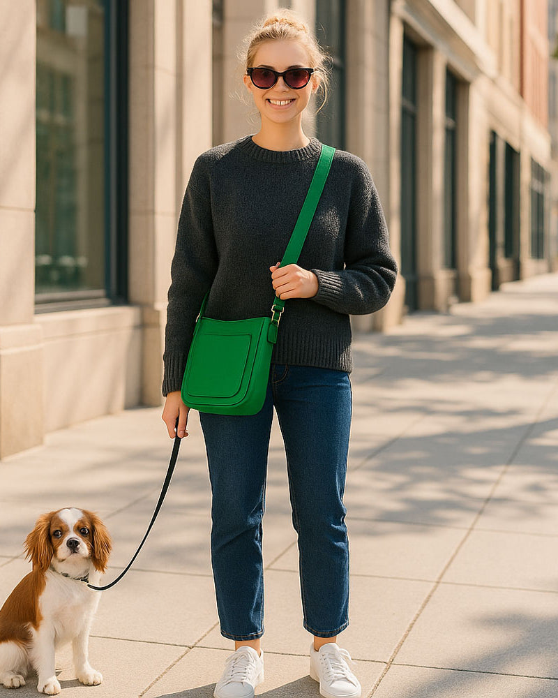 Woman walking a dog on a city street, holding a green bag