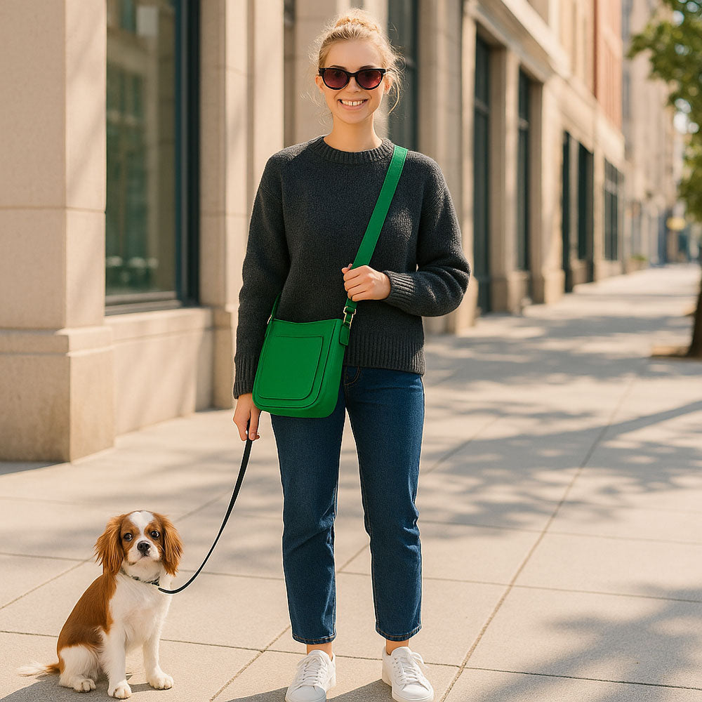 Woman walking a dog on a city street, holding a green bag