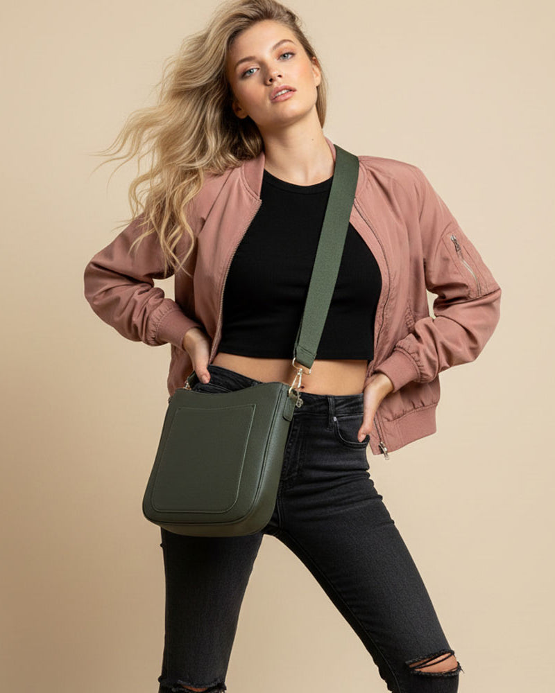 Woman wearing a army crossbody bag against a beige background