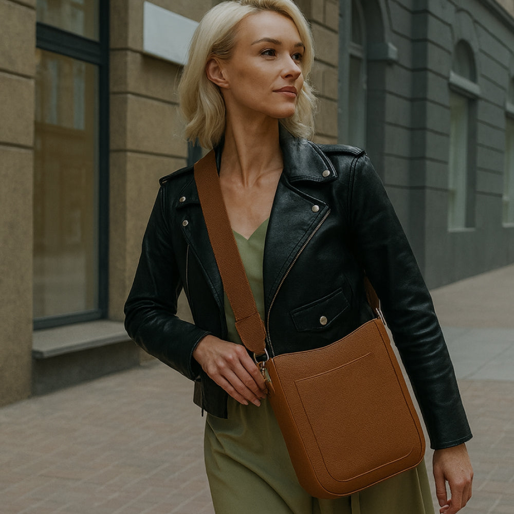 Woman walking down a city street, wearing a camel crossbody handbag.