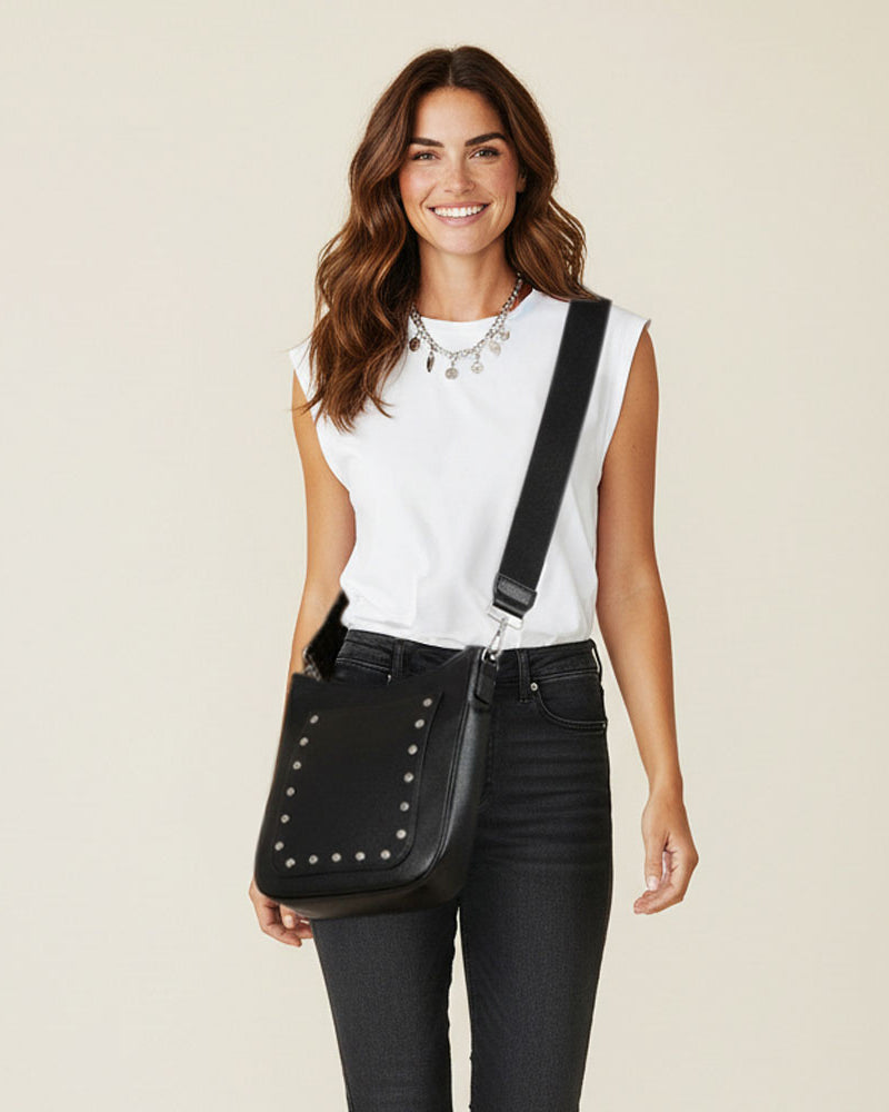 Woman holding a black studded bag against a beige background