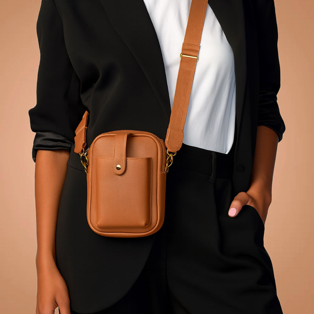 A woman wearing the Maya crossbody bag in Camel against a beige background