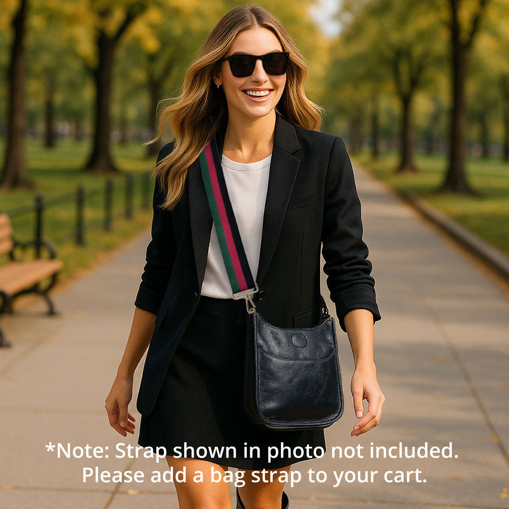 Woman walking in the park wearing a black messenger bag. Text: Note-Strap in photo not included.  Please add a bag strap to your cart.