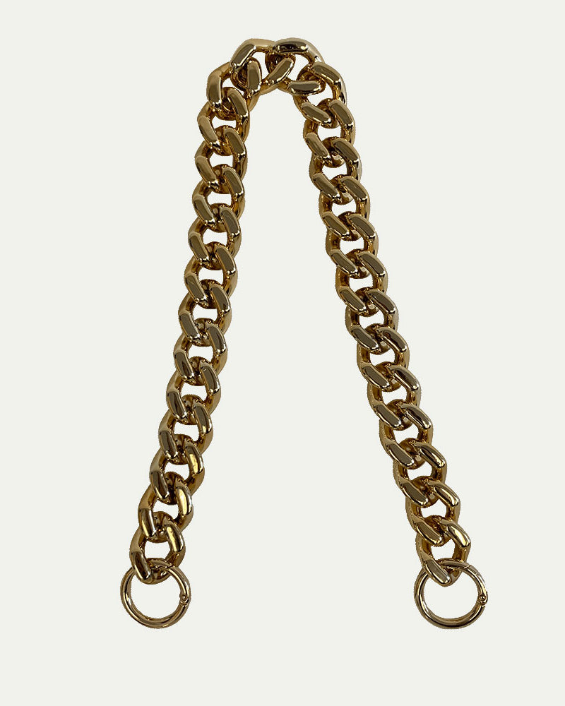 Chunky resin gold shoulder bag strap with gold hardware on a light grey background
