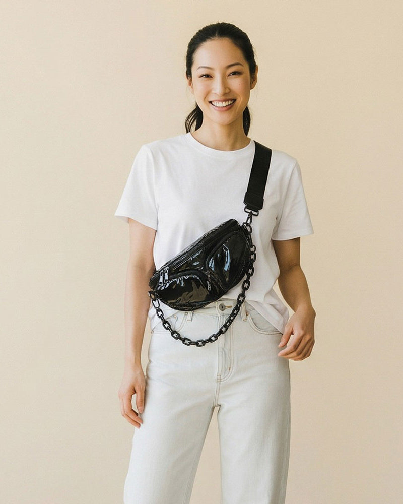 Woman wearing a black liquid nylon sling bag on a beige background