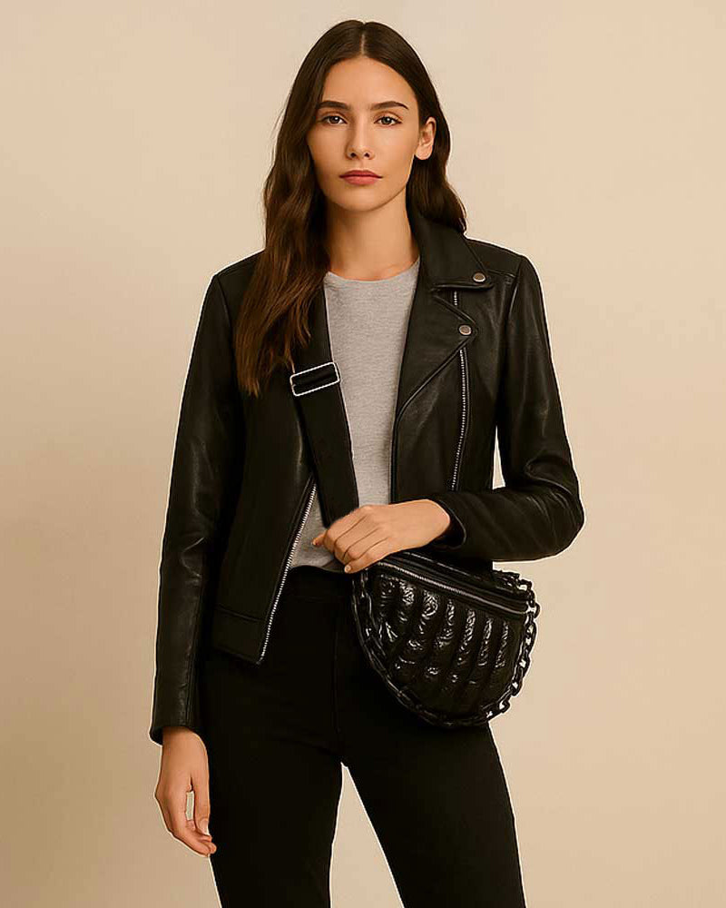 Woman wearing a black sling bag in front of a beige background
