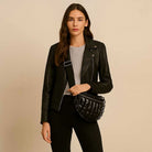 Woman wearing a black sling bag in front of a beige background