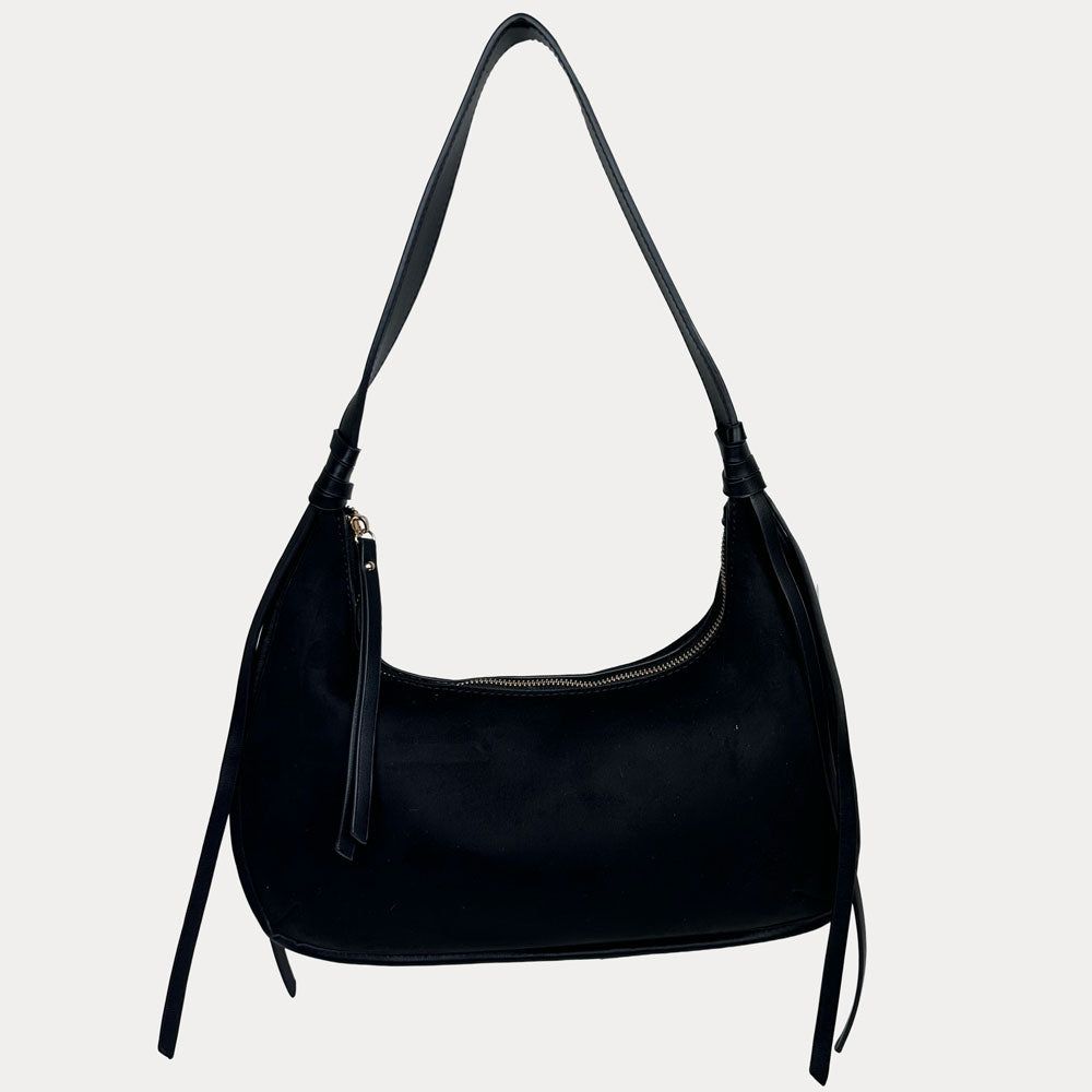 A black vegan suede shoulder bag with a vegan leather details, shown against a light gray