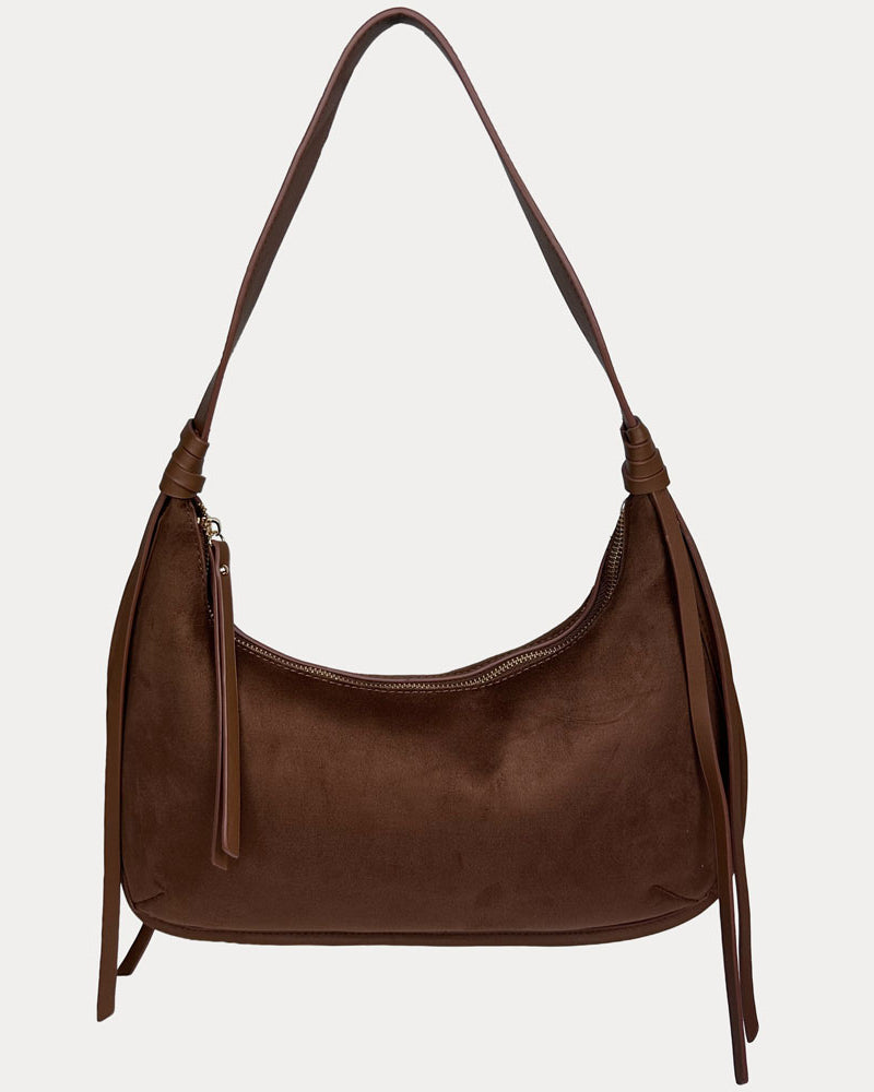 A chocolate vegan suede shoulder bag with a vegan leather details, shown against a light gray