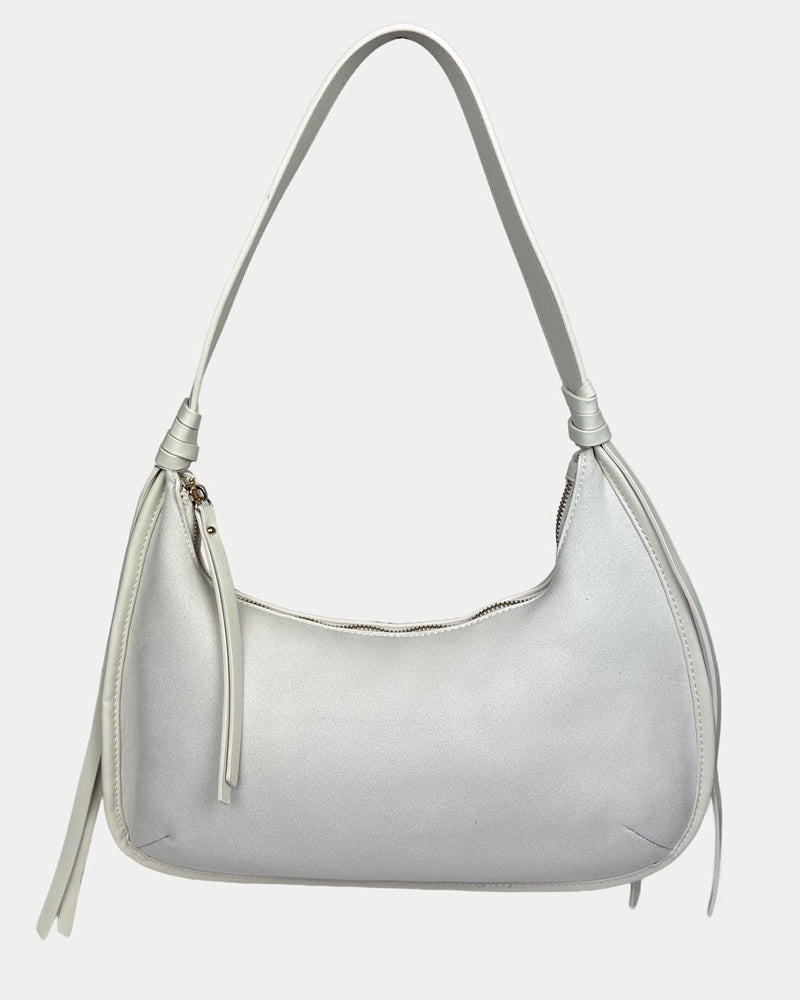 A cream vegan suede shoulder bag with a vegan leather details, shown against a light gray