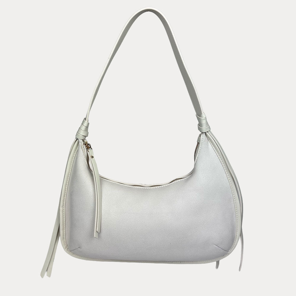 A cream vegan suede shoulder bag with a vegan leather details, shown against a light gray