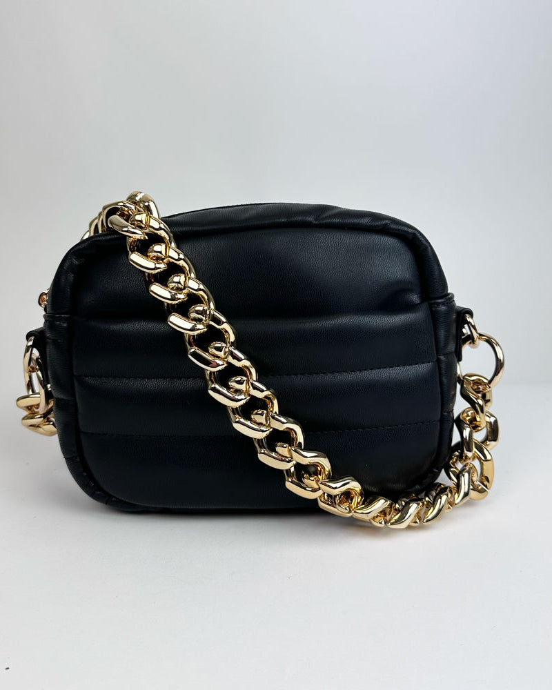 A black handbag with a gold chunky resin interchangeable chain shoulder strap.