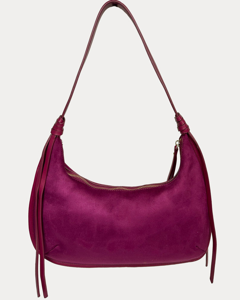A burgundy vegan suede shoulder bag with vegan leather strap and hanging tassels, shown against a light gray background.