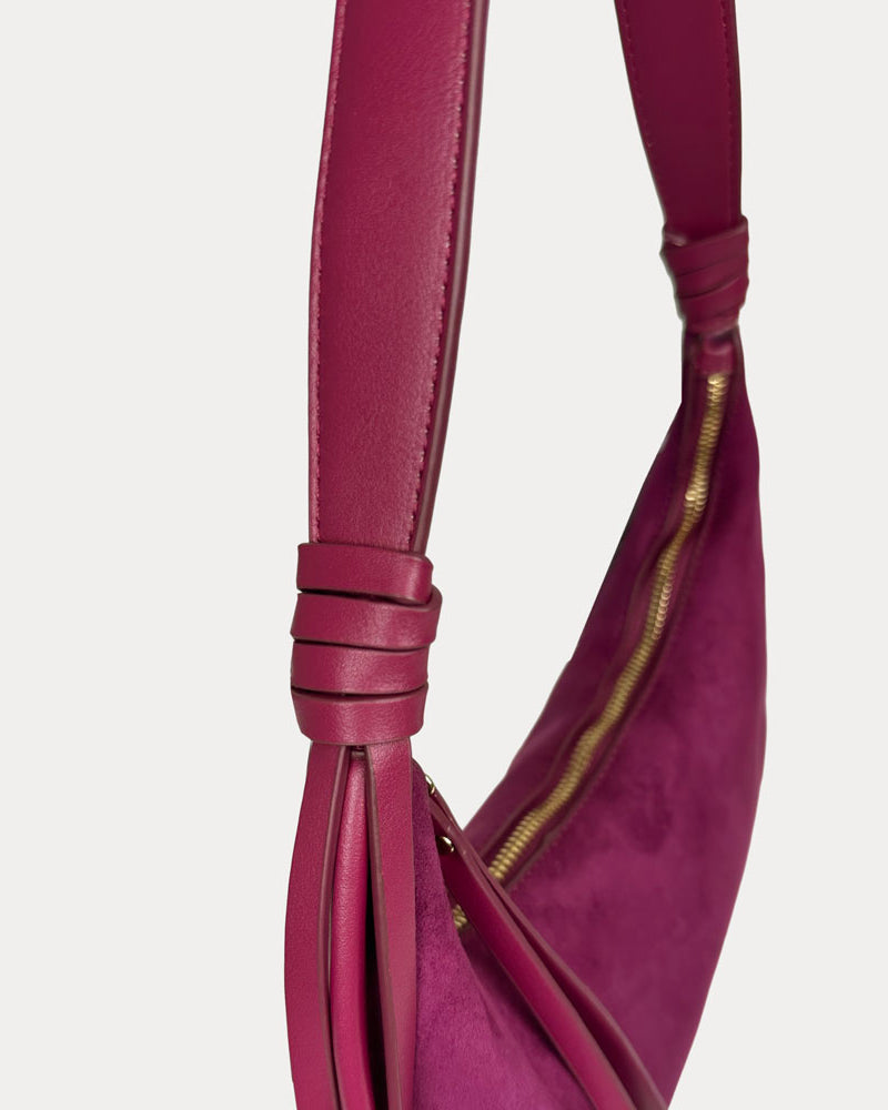 A close-up of a burgundy leather shoulder bag strap, set against a light gray background.