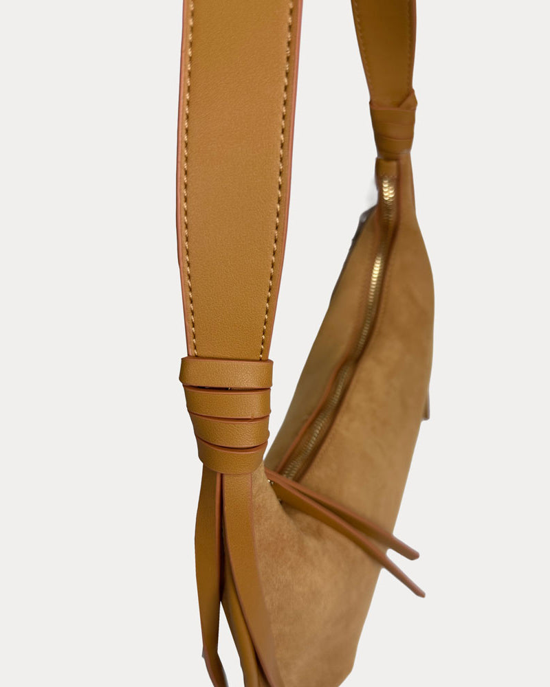 A close-up of a camel vegan leather shoulder bag strap, set against a plain light gray background.