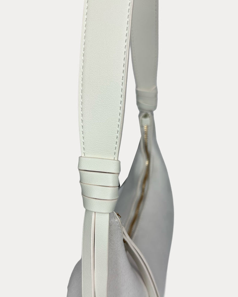 A close-up of a cream shoulder bag with a vegan leather strap.