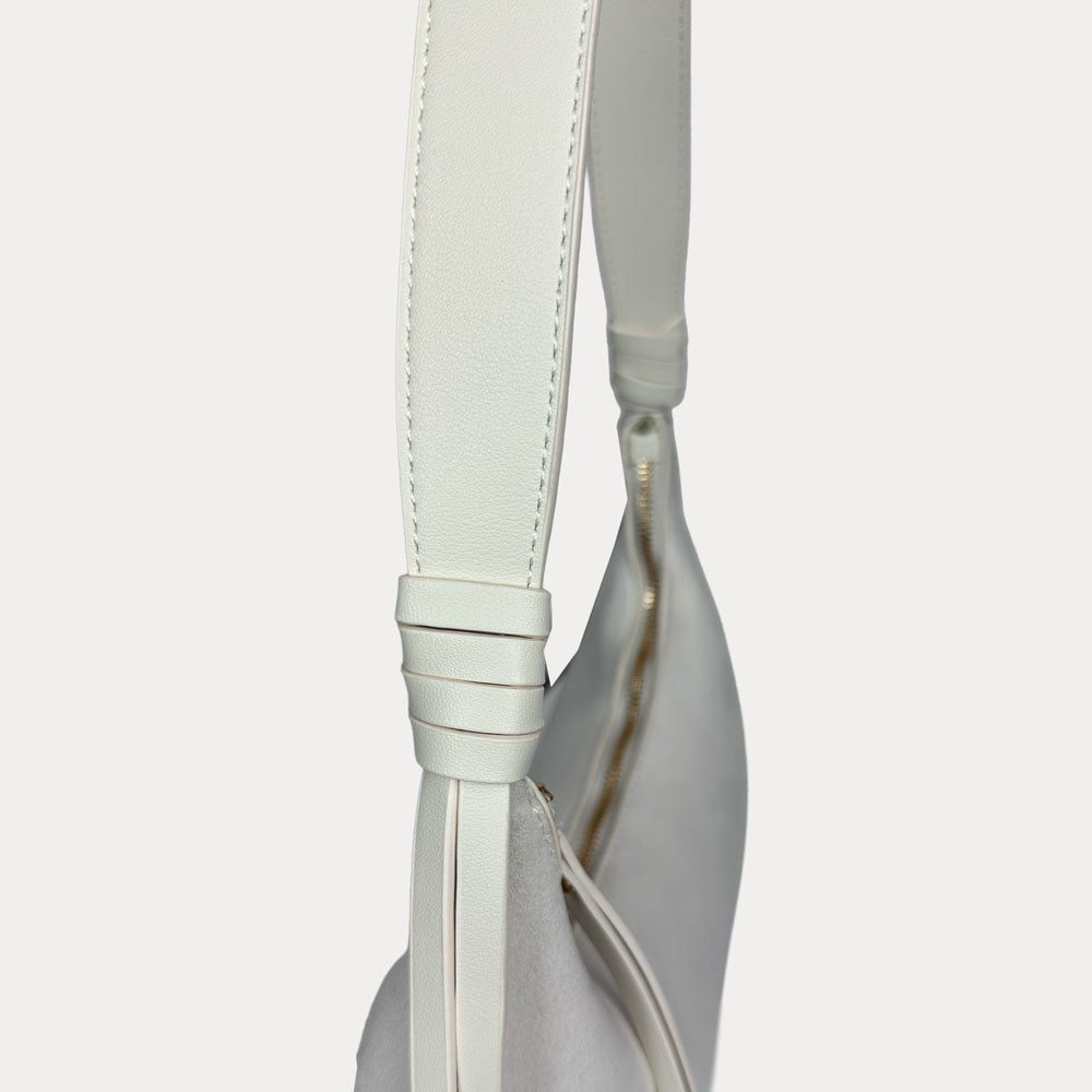 A close-up of a cream shoulder bag with a vegan leather strap.