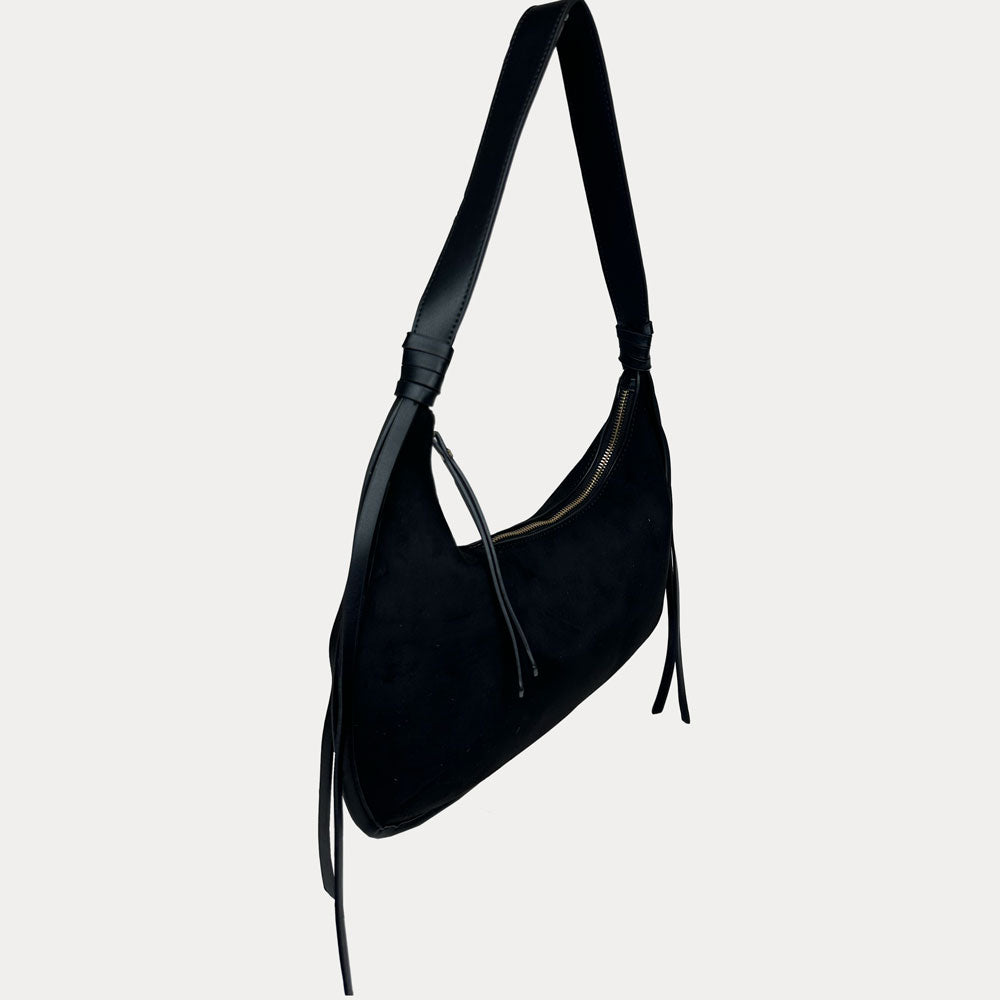 A black vegan suede shoulder bag with a vegan leather strap and hanging tassels, shown against a light gray background.