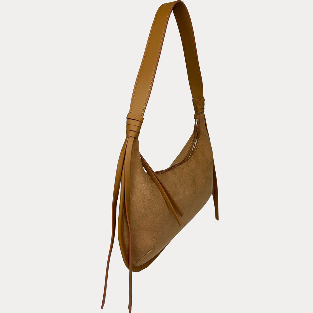 A camel vegan suede shoulder bag with a vegan leather strap and hanging fringe details, shown from a side profile on a light gray background.