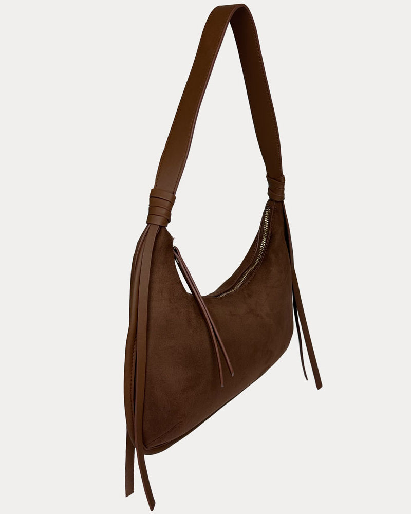 A chocolate vegan suede shoulder bag with a vegan leather strap and hanging fringe details, shown against a light gray background.
