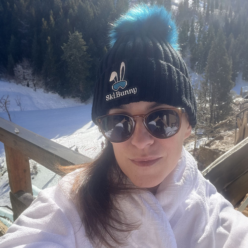 woman wearing the black ski bunny hat with blue moon pom pom and blue moon ski bunny patch