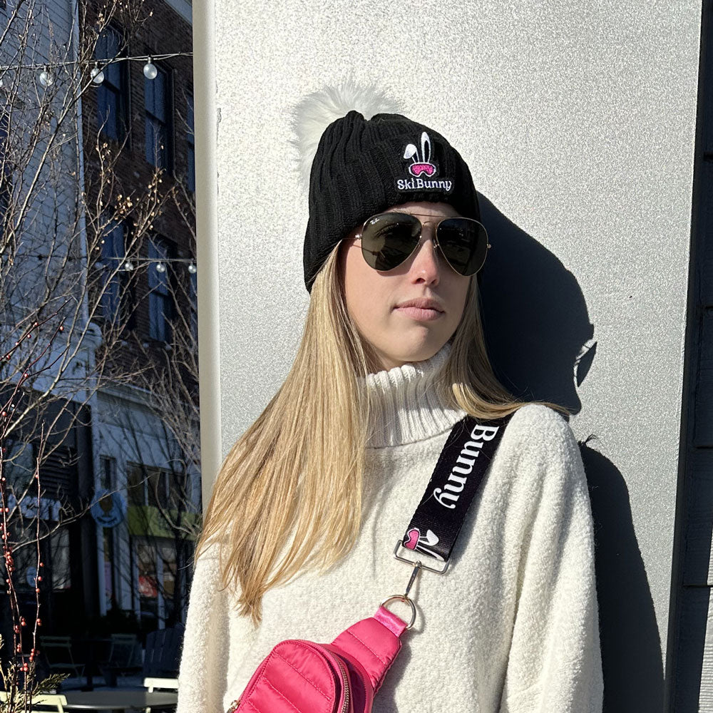 woman wearing the black ski bunny hat with white pom pom and pink ski bunny patch
