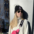 woman wearing the black ski bunny hat with white pom pom and pink ski bunny patch