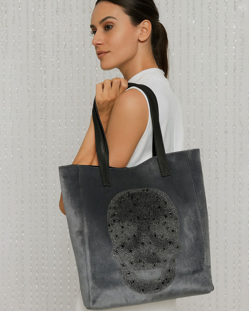 Woman holding the Sophie Grey Tote with rhinestone skull over her shoulder. Neutral Background