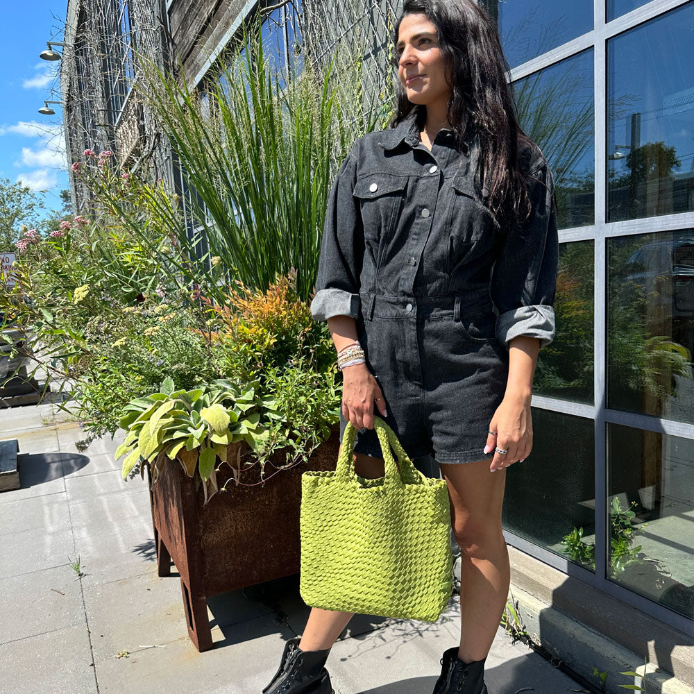 Woman holding chartreuse woven neoprene tote at the handles