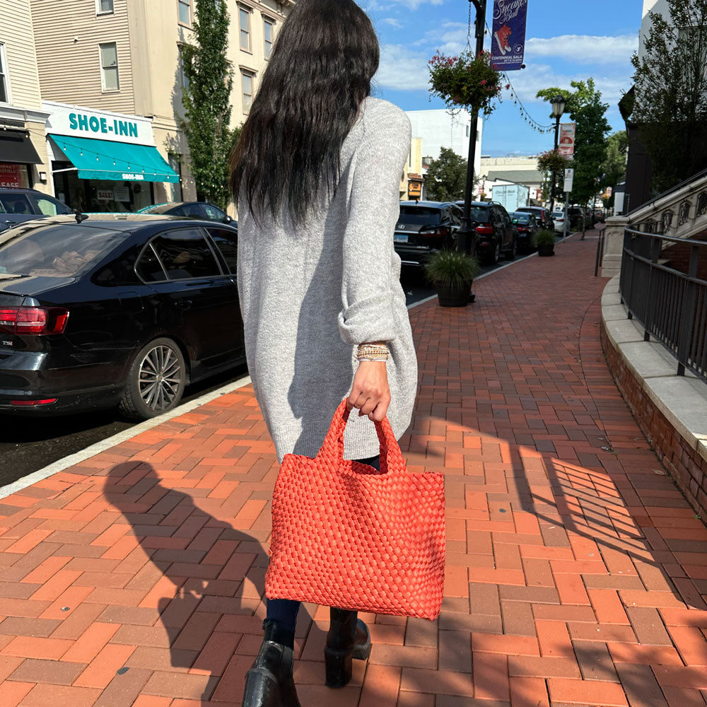 Women walking with Pumpkin Woven Neoprene Tote, holding it at the handles