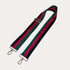 Black, red, and green striped bag strap with gold hardware on a light gray background,