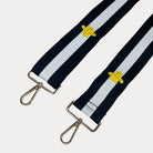 Black and white striped bag strap with embroidered yellow bees with gold hardware on a light gray background