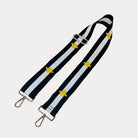Black and white striped bag strap with embroidered yellow bees with gold hardware on a light gray background