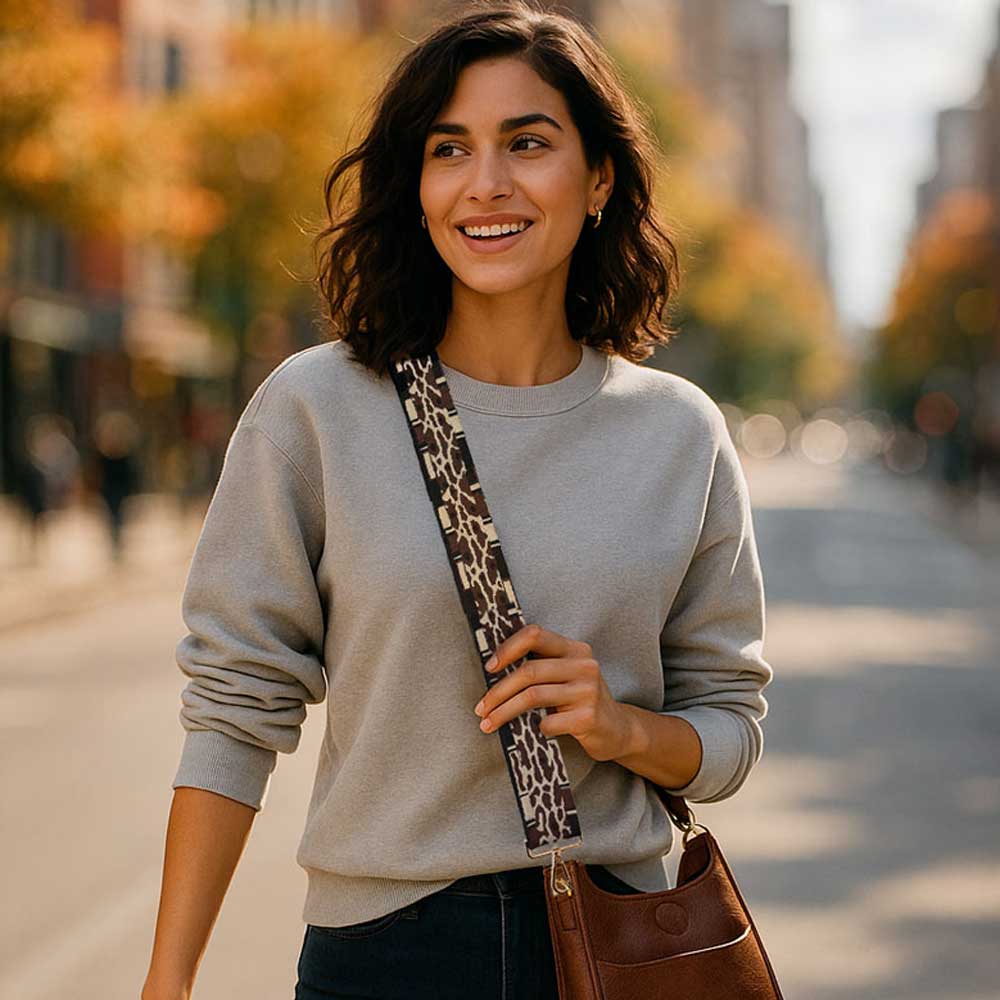Woman walking on a street holding a brown bag with a leopard print strap