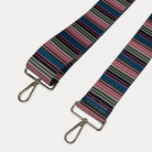 Multi colored striped bag strap with gold hardware on a light gray background