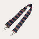 Multi colored striped bag strap with gold hardware on a light gray background