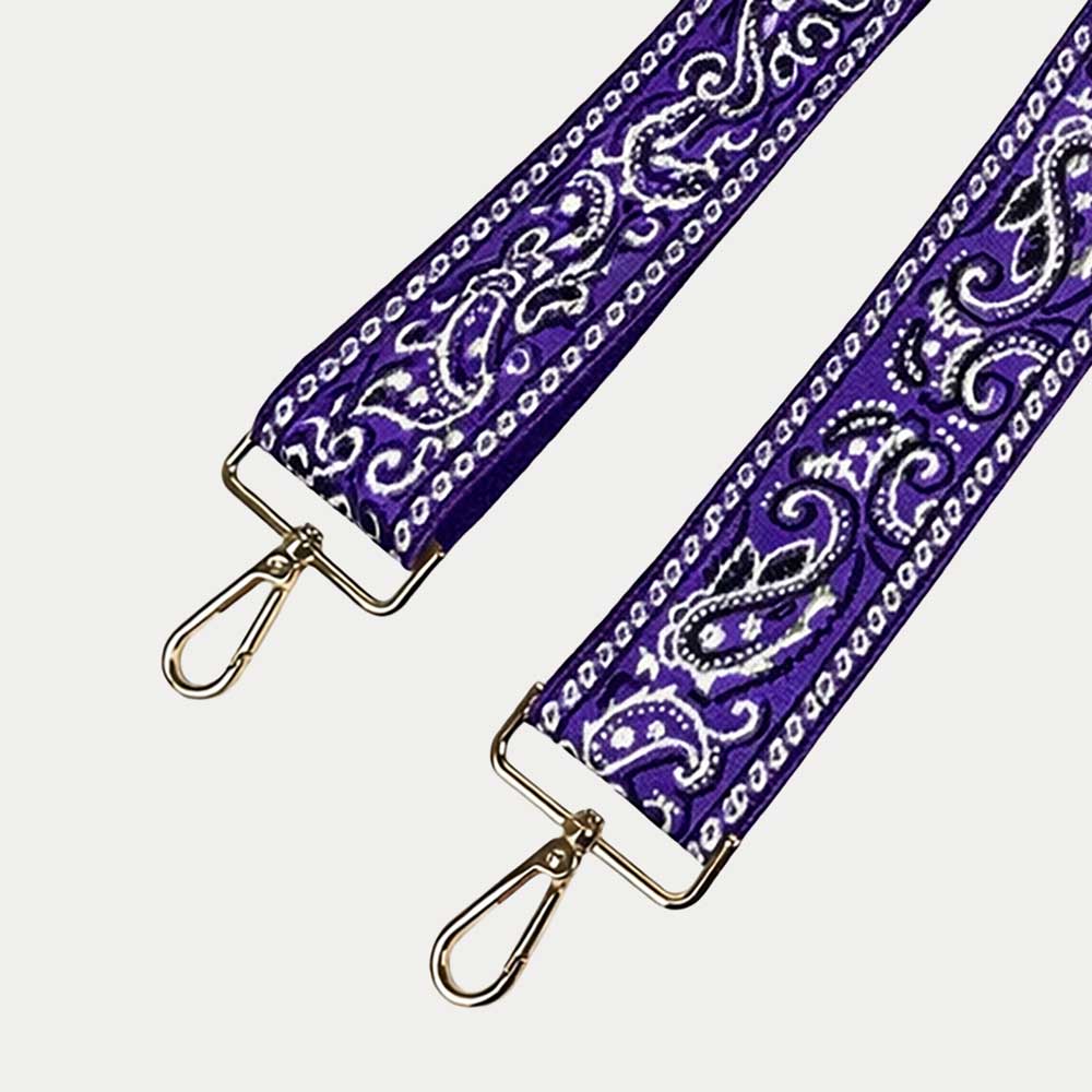 Purple paisley patterned strap with gold hardware on a light gray 