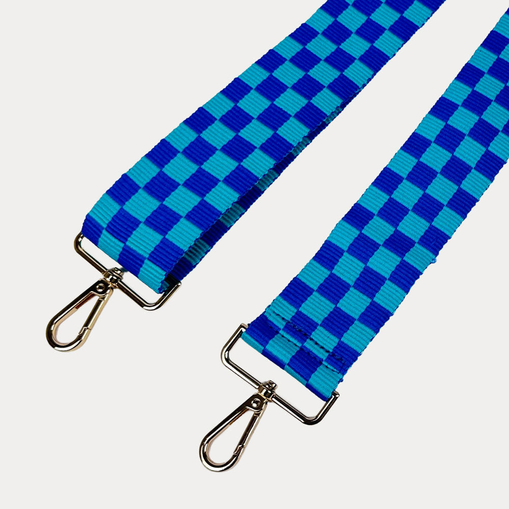 Blue and aqua checkered bag strap  with gold metal clasp trim on a white background