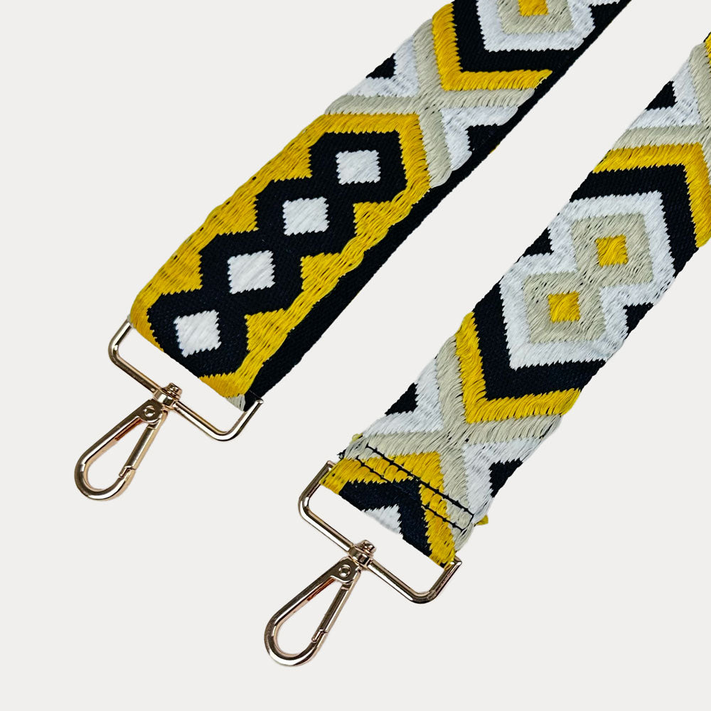 Embroidered strap with geometric pattern with gold metal clasps on a white background