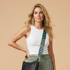 Woman wearing a black handbag with a zebra bag strap against a beige background