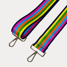 Bright multi colored striped bag strap with gold hardware on a light gray background