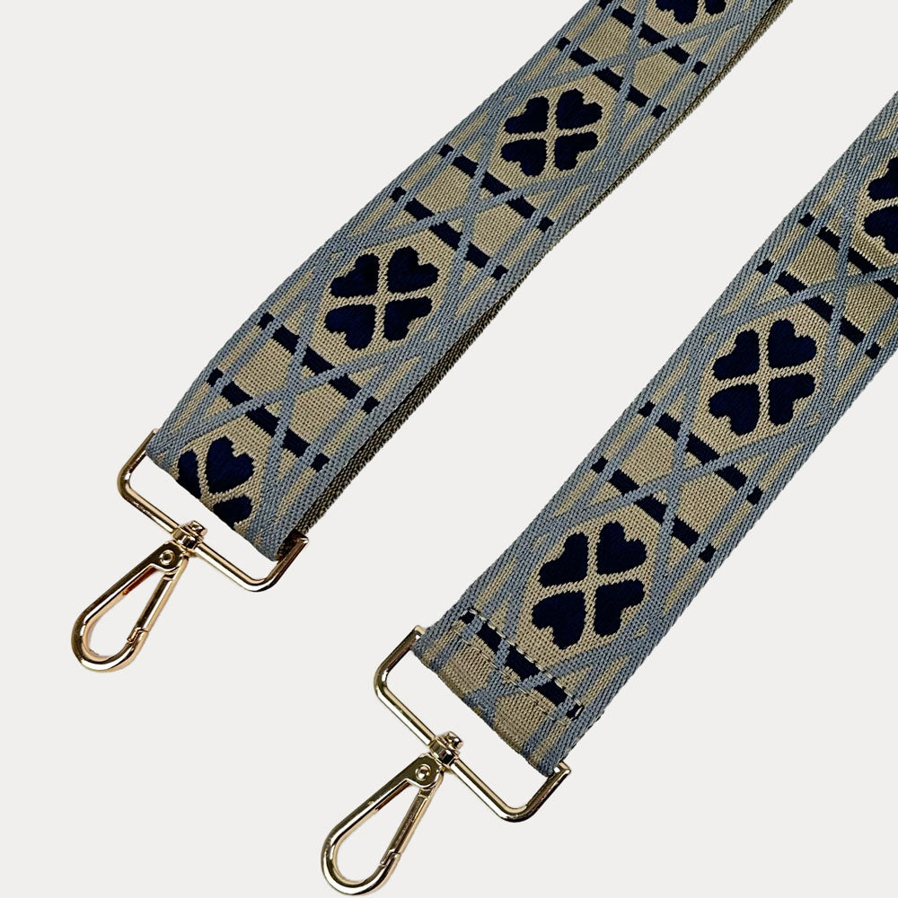 Taupe, light blue, navy patterned bag strap with gold metal clasps on a light grey background.