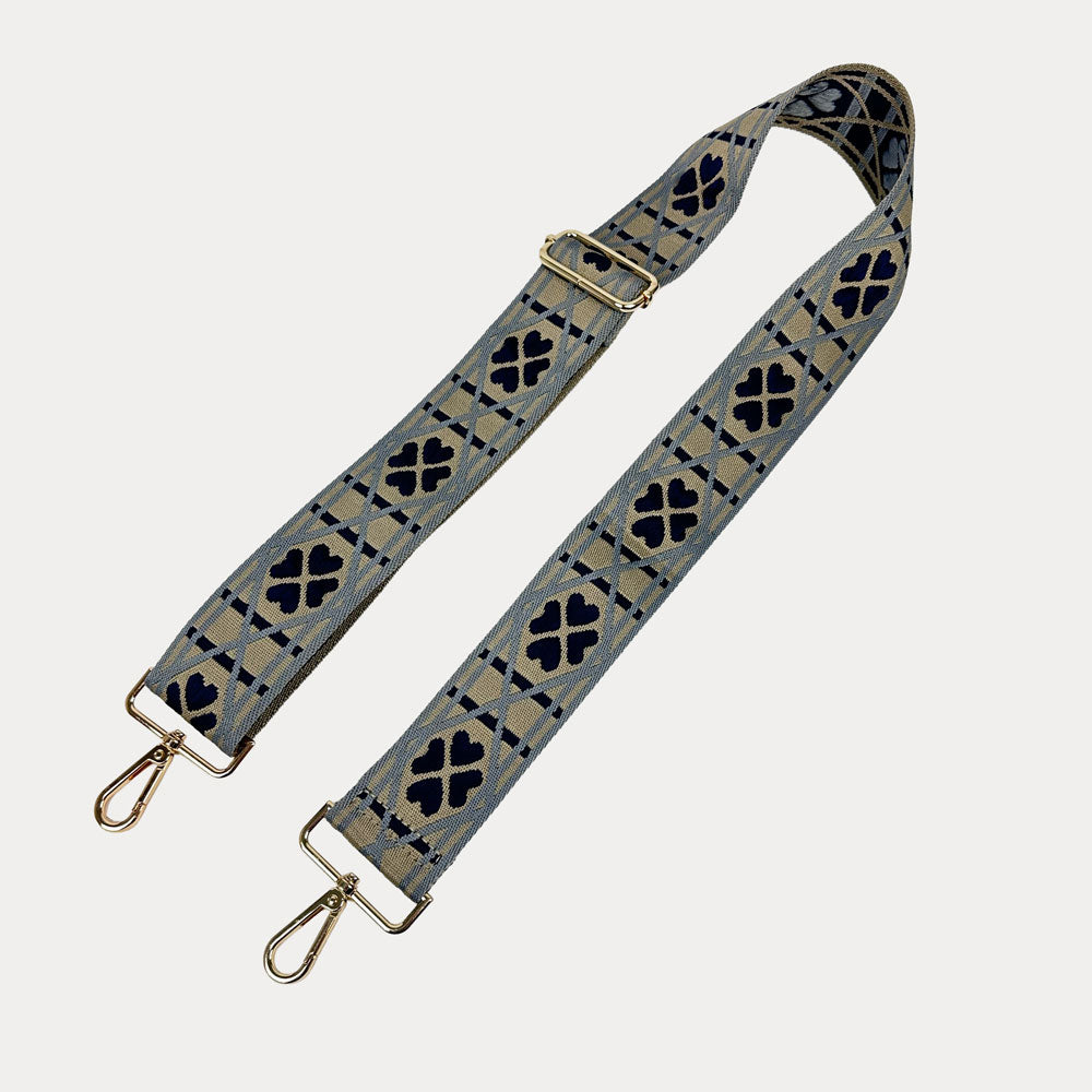 Taupe, light blue, navy patterned bag strap with gold metal clasps on a light grey background.