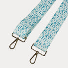 Aqua and white dot patterned bag strap with gold hardware on a light gray background