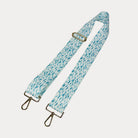Aqua and white dot patterned bag strap with gold hardware on a light gray background