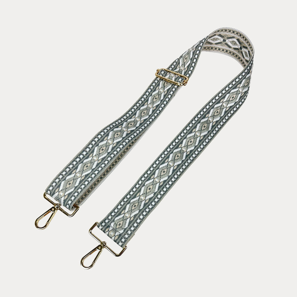 Grey, white, tan diamond patterned bag strap with gold metal clasps on a light gray background